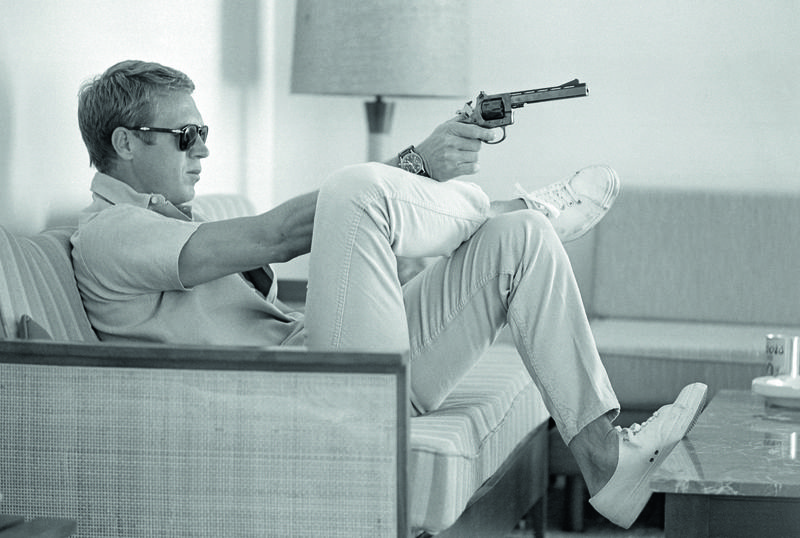 7. Steve McQueen aims a pistol in his living room